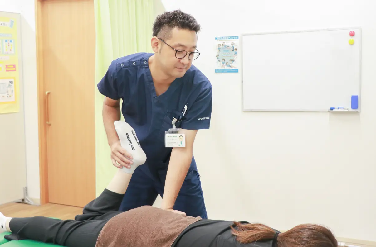うつぶせの患者様の脚を院長が支えながら施術している様子
