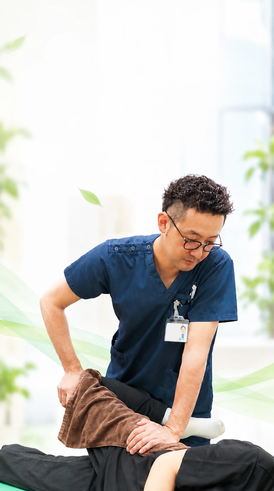 院長が横向きに寝た患者様の腰と股関節に手を当てて施術している様子